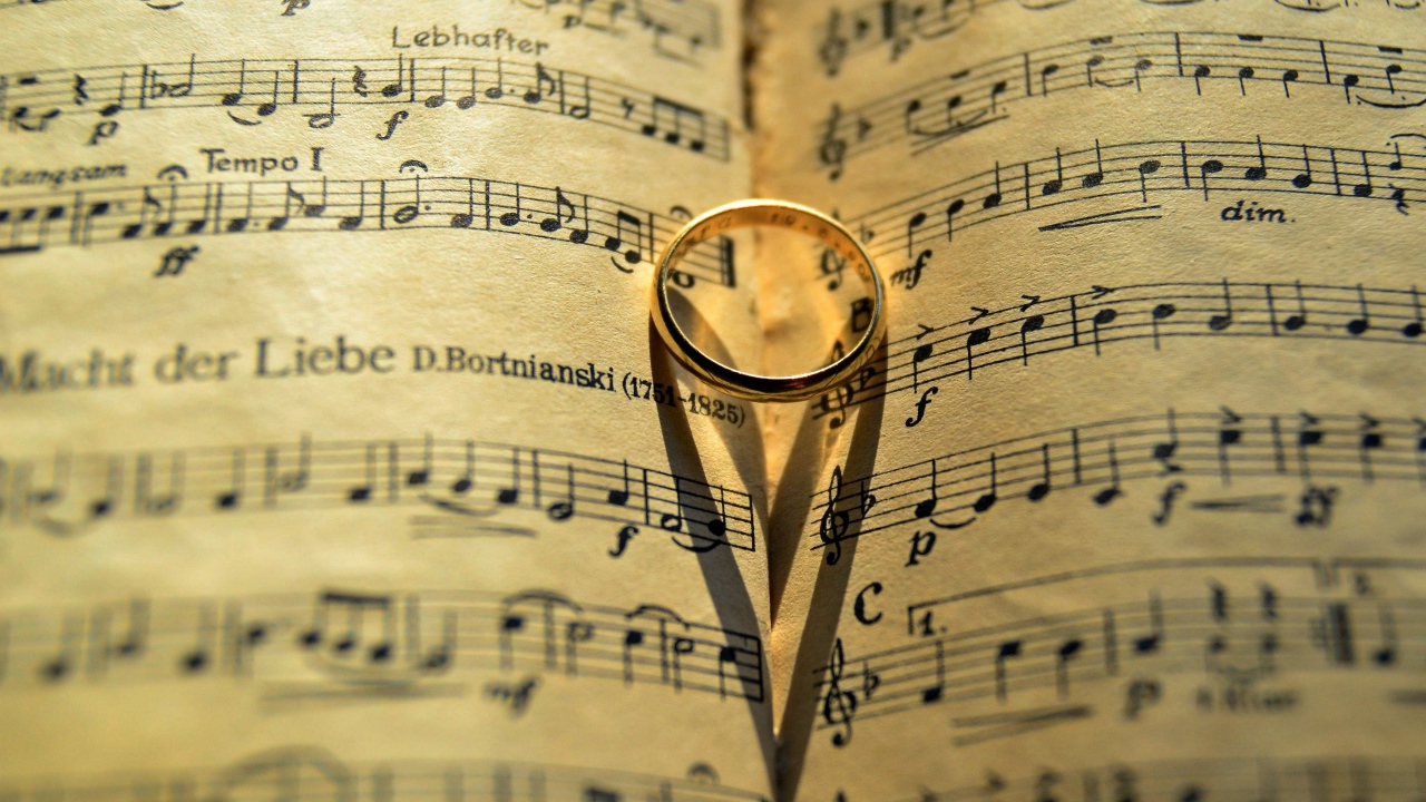 Золотое обручальное кольцо лежит на нотной тетради