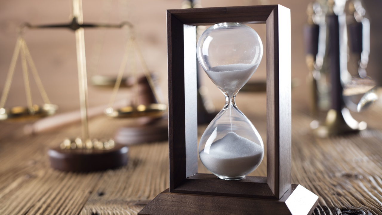 Песочные часы на столе с весами крупным планом