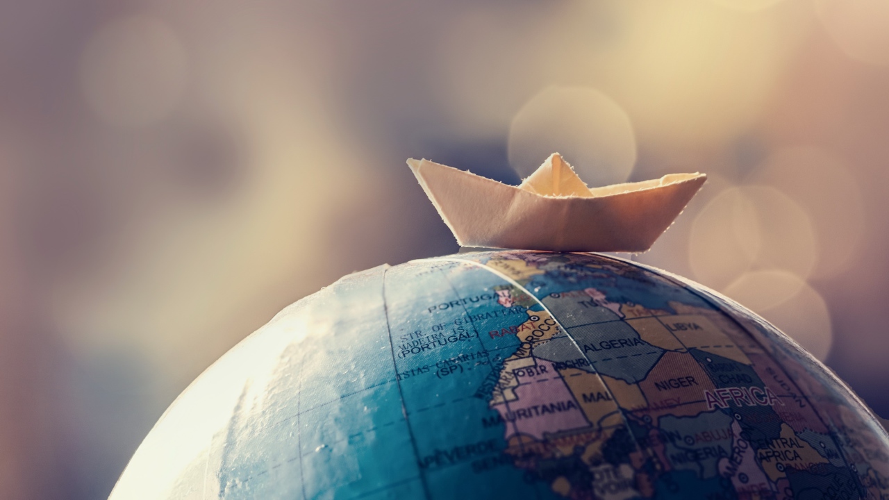 Бумажный кораблик лежит на глобусе