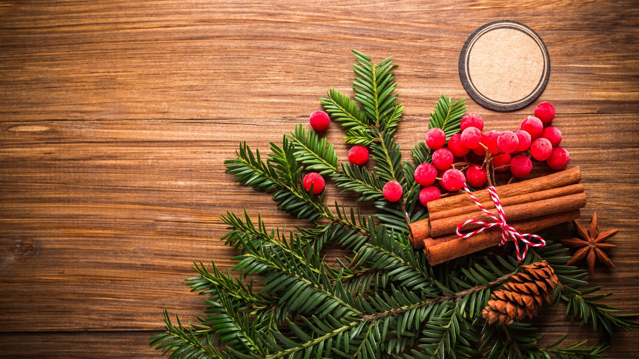 Еловая ветка, корица, ягоды рябины и шишки на деревянном фоне