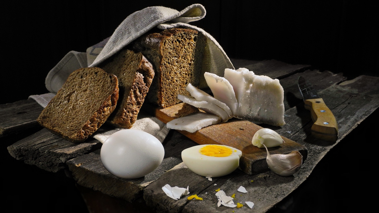 Черный хлеб, вареные яйца, чеснок и сало на деревянном столе