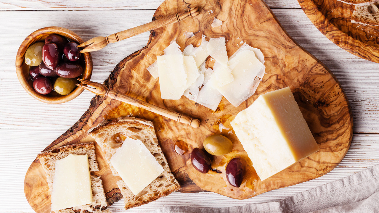 Сыр на доске с хлебом и и оливками