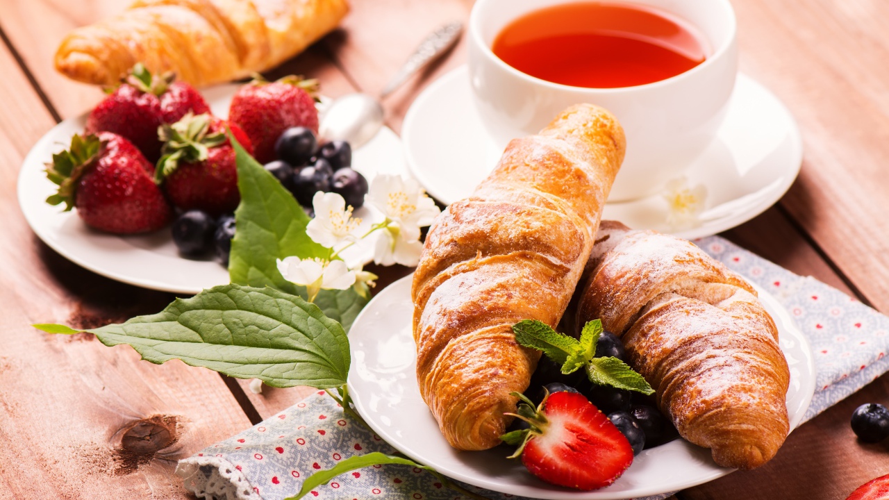 Круассаны на столе с ягодами и чашкой чая