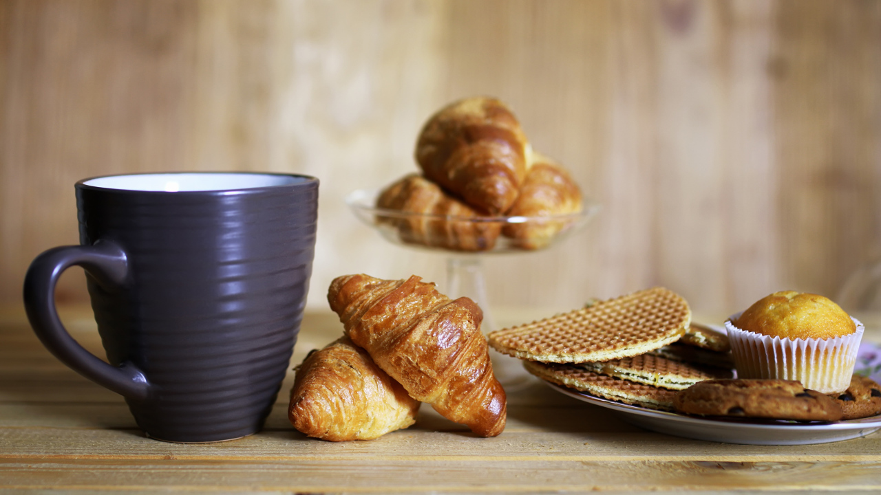 Чашка на столе с круассанами и вафлями 