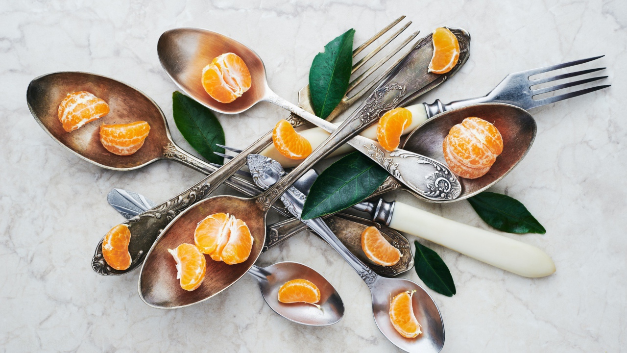 Столовые приборы на столе с дольками мандарина