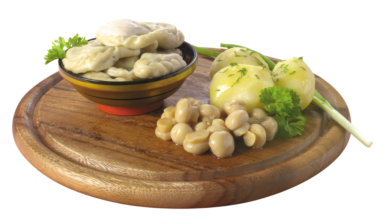 Вареники с грибами и вареной картошкой на деревянной доске на белом фоне