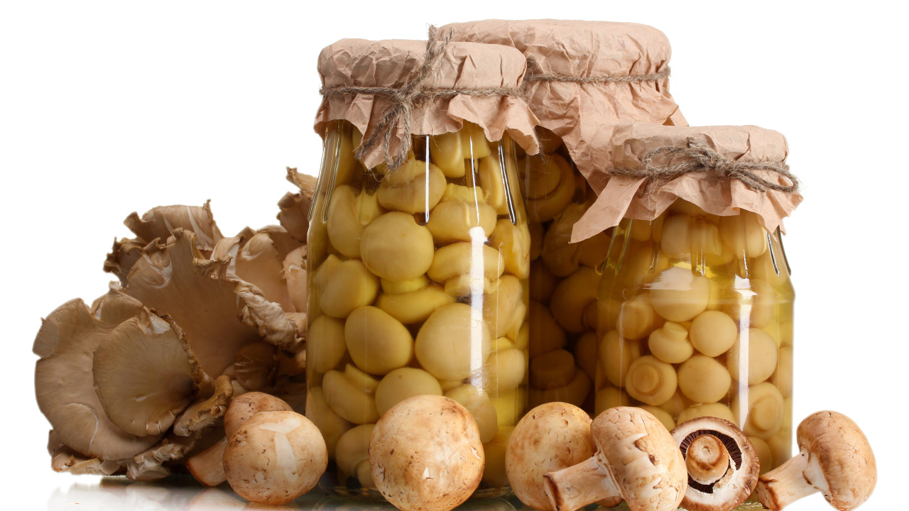 Маринованные шампиньоны в банках на белом фоне со свежими