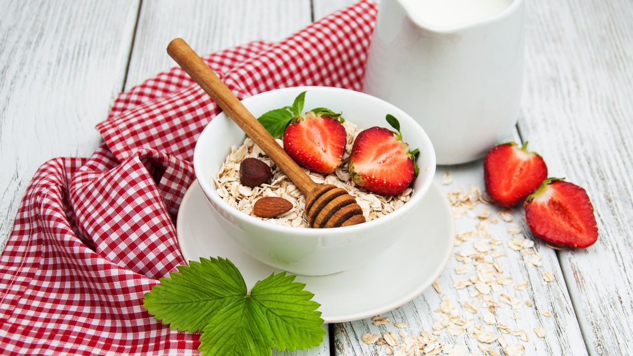 Овсяная каша на столе с молоком и клубникой