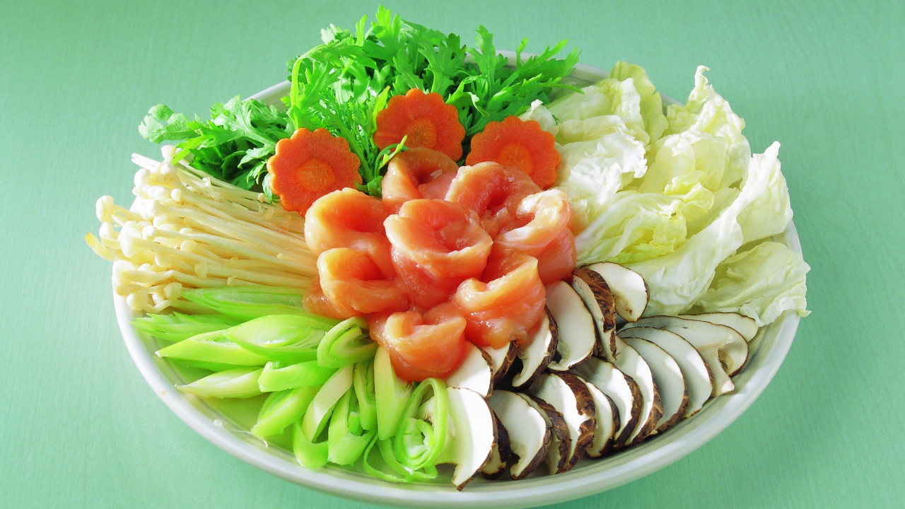 Тарелка с овощами и красной рыбой на зеленом фоне