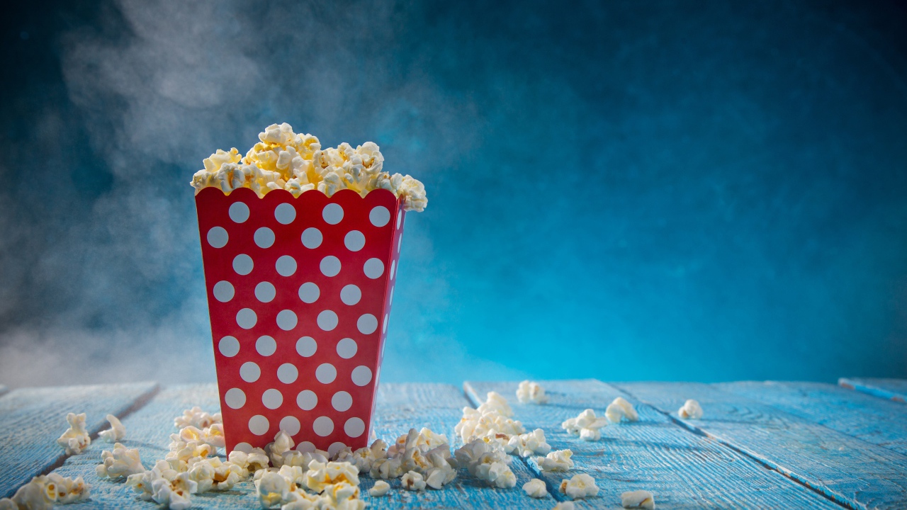 Попкорн в картонном пакете на голубом столе 