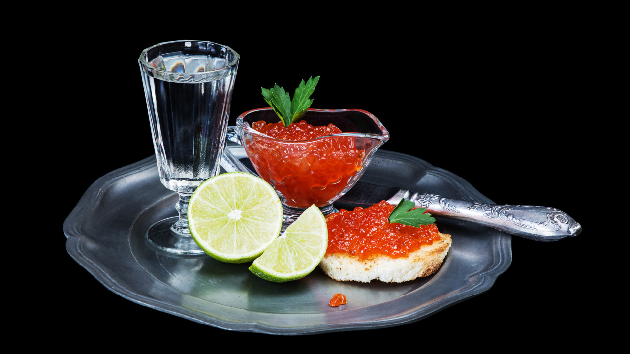 Бутерброды с красной икрой на подносе с рюмкой водки и лаймом