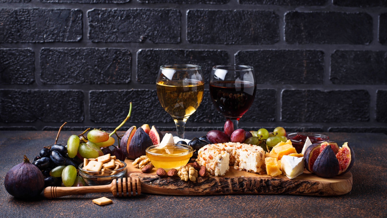 Два бокала вина на столе с сыром, инжиром и виноградом