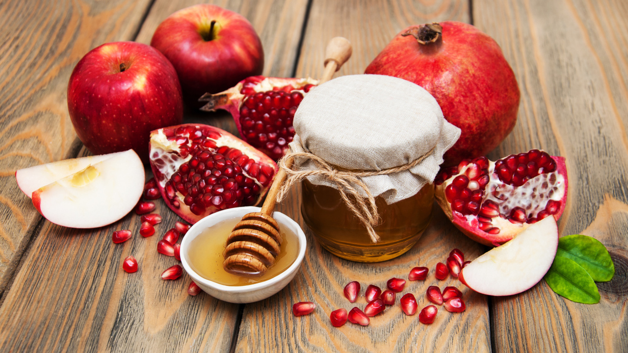 Банка меда на столе с гранатами и яблоками