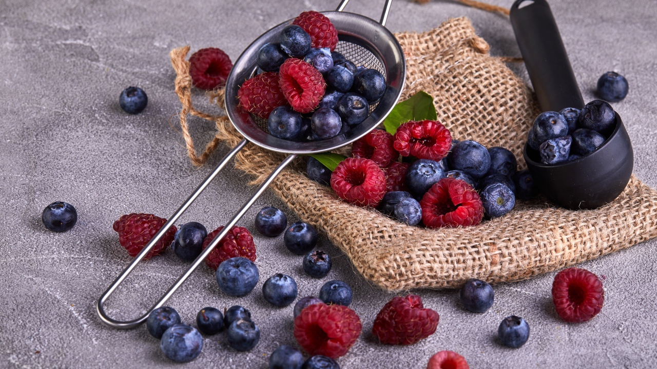 Ягоды черники и малины на столе с ситом