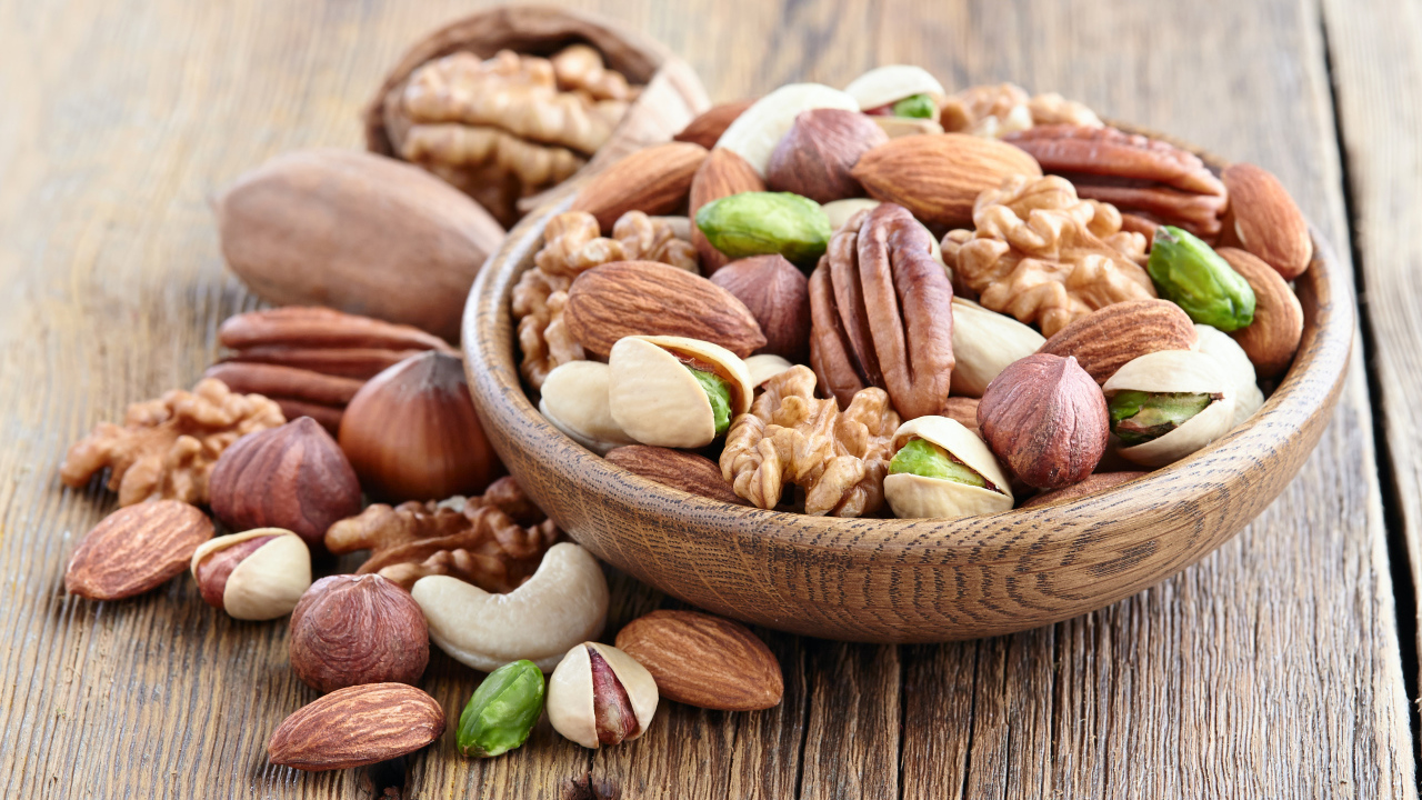 Разные орехи в деревянной тарелке на столе