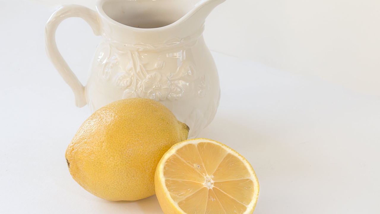 Лимон с белым кувшином на сером фоне