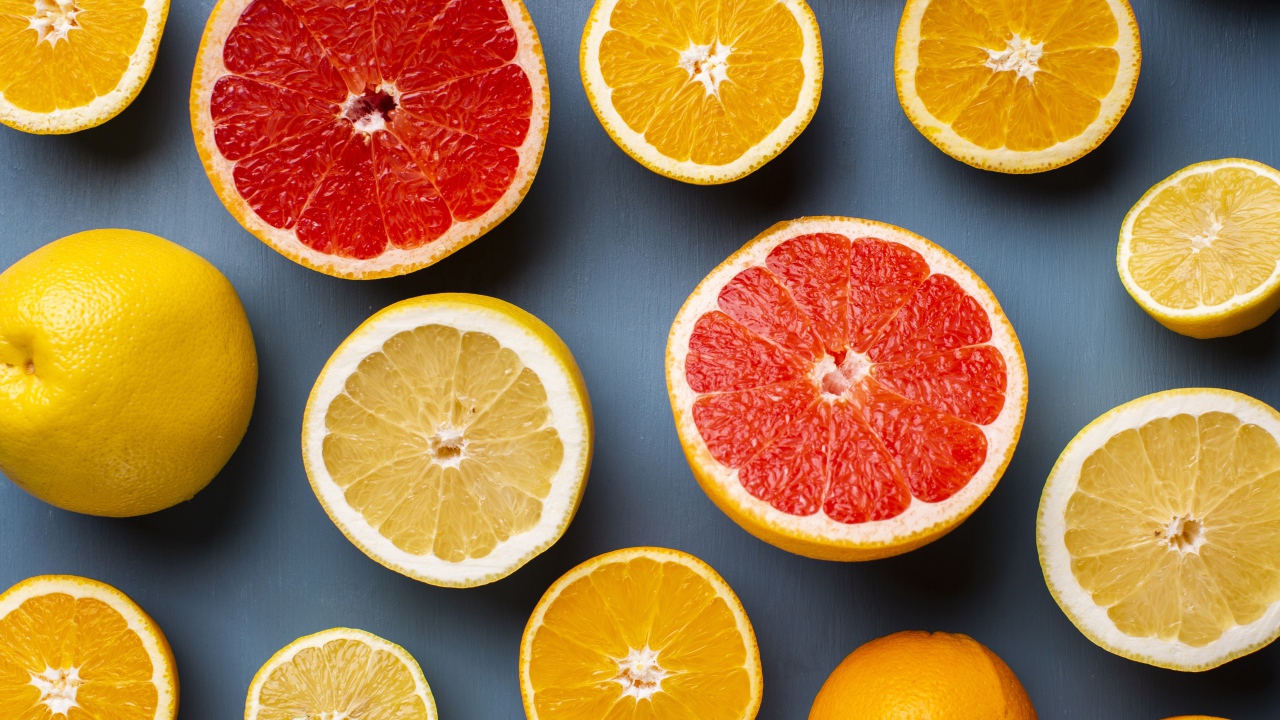 Лимоны, грепфрукты и апельсины на сером фоне