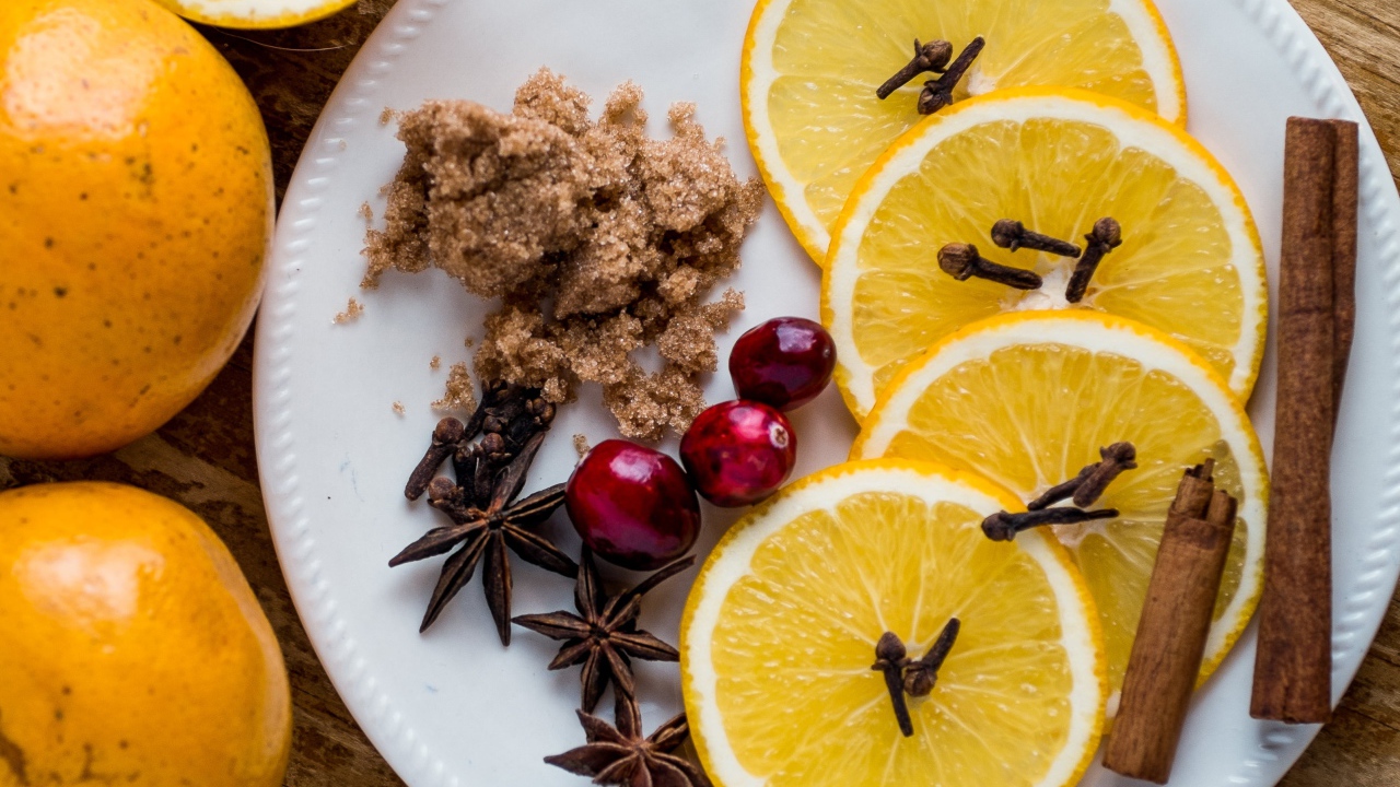 Круги апельсина на тарелке с сахаром, корицей и бадьяном