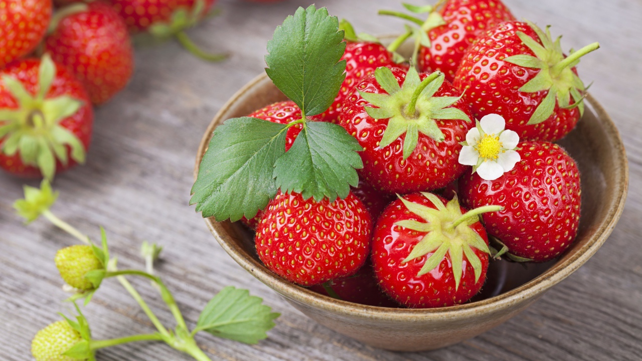 Спелая красная клубника в миске на столе 