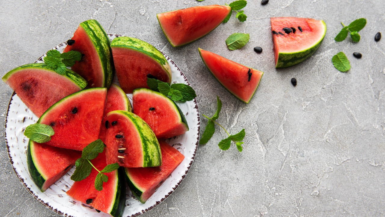 Полосатый арбуз нарезан кусочками на тарелке