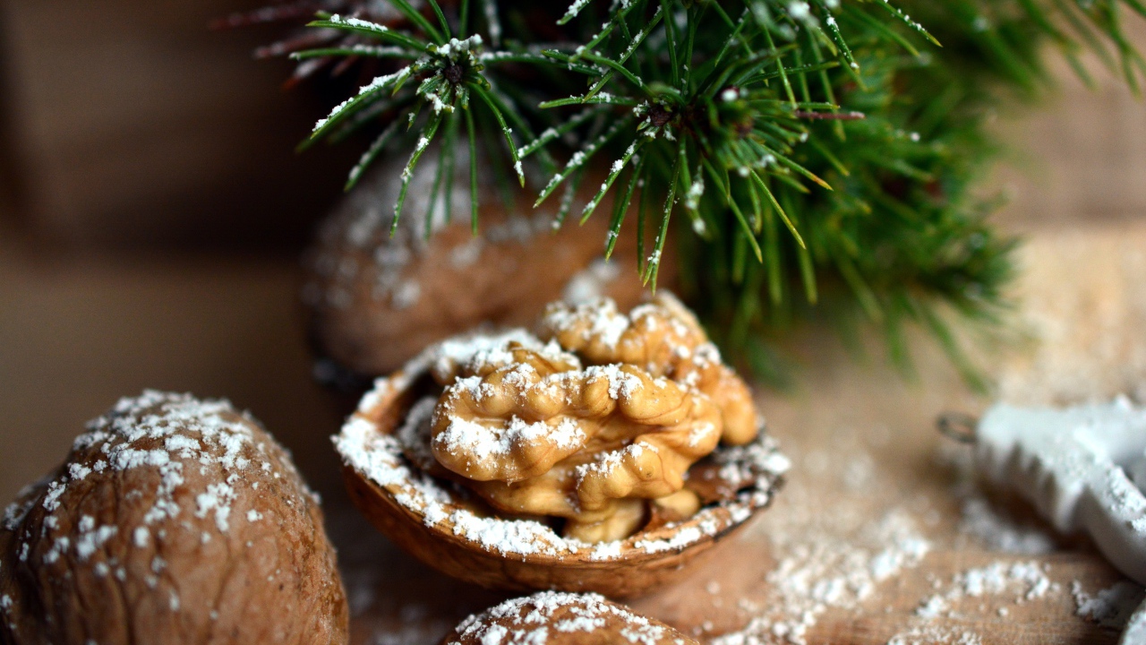 Грецкие орехи посыпанные сахарной пудрой на столе с еловой веткой