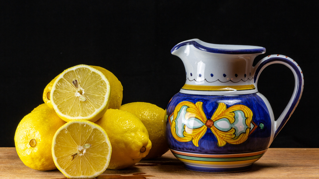 Желтые лимоны на столе с кувшином