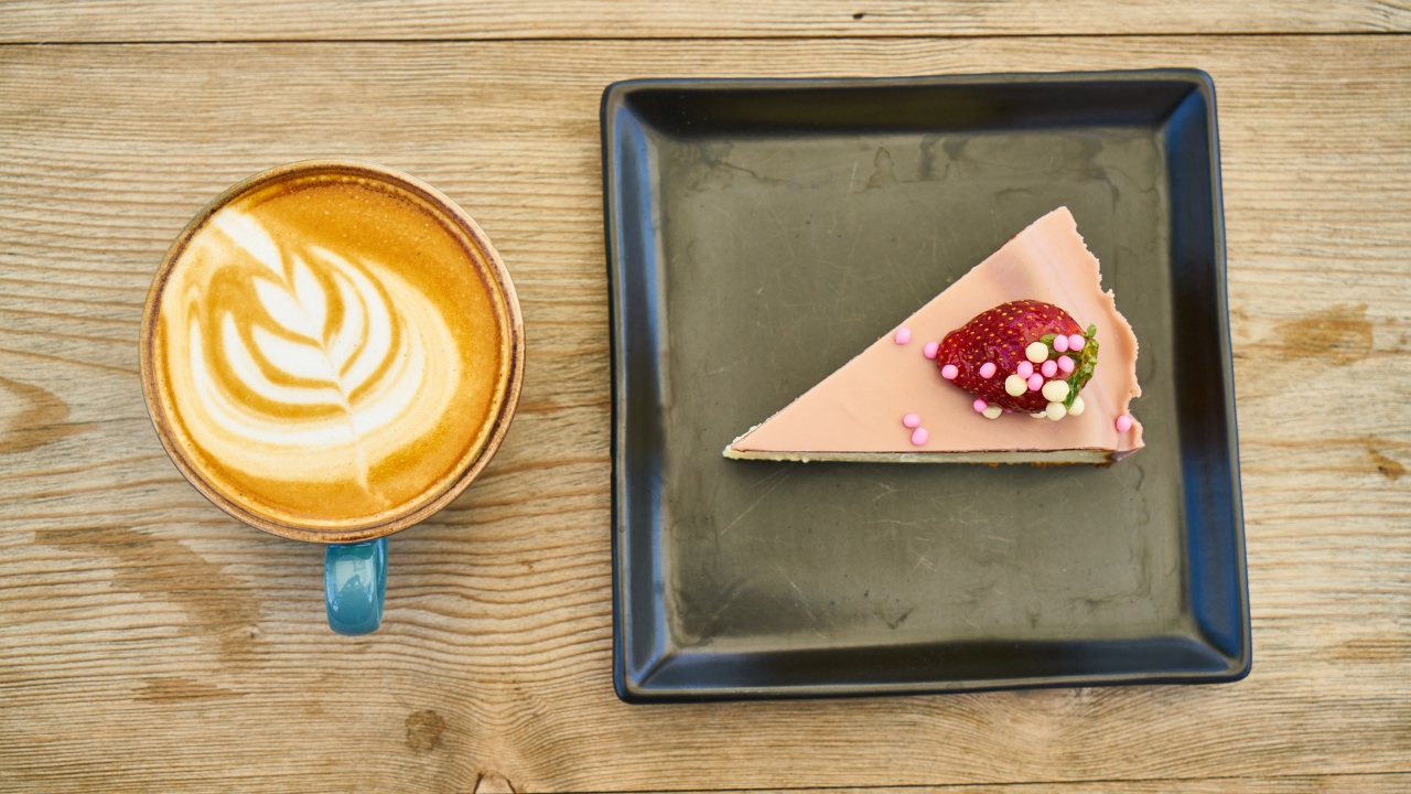 Кусок торта на черной тарелке с кофе