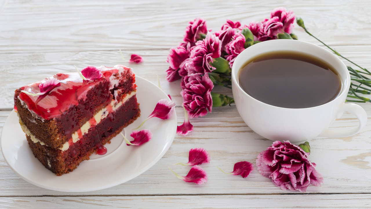 Кусок торта на столе с букетом гвоздик и чашкой кофе