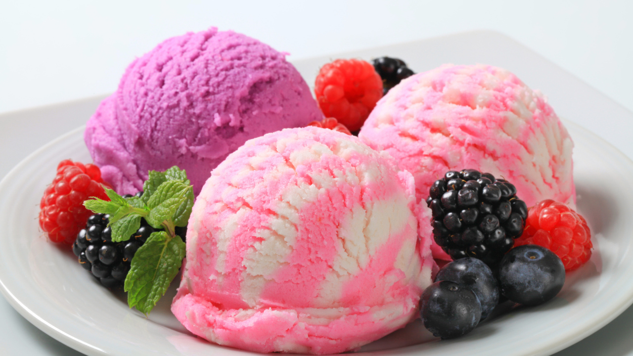 Шарики фруктового мороженого на белой тарелке с ягодами
