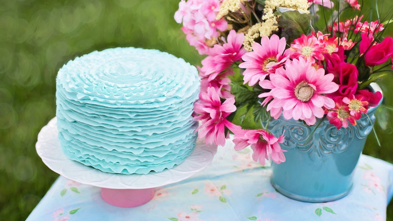 Красивый торт с голубой глазурью на столе с букетом