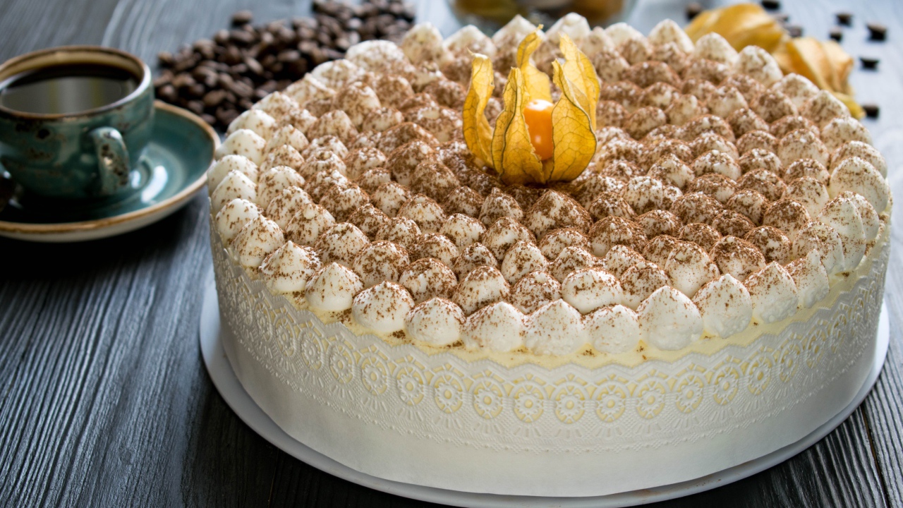 Красивый праздничный торт с цветком физалиса на столе с кофе