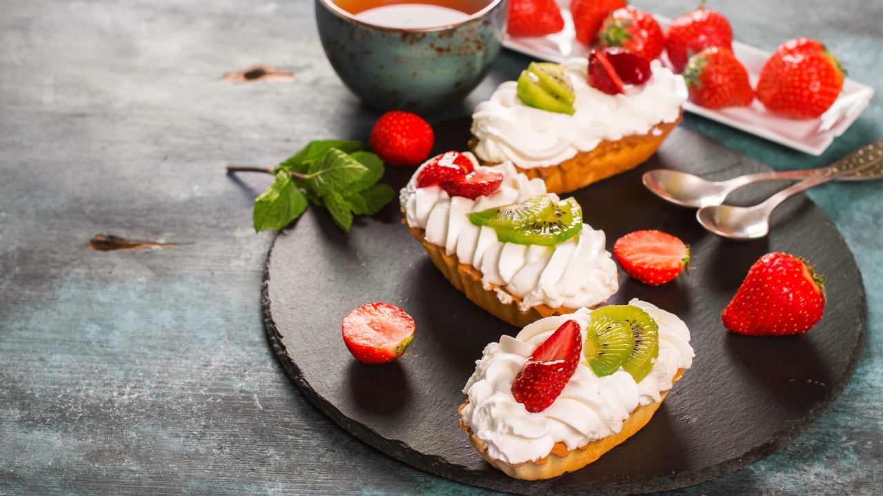 Пирожные с киви и клубникой на столе с чаем