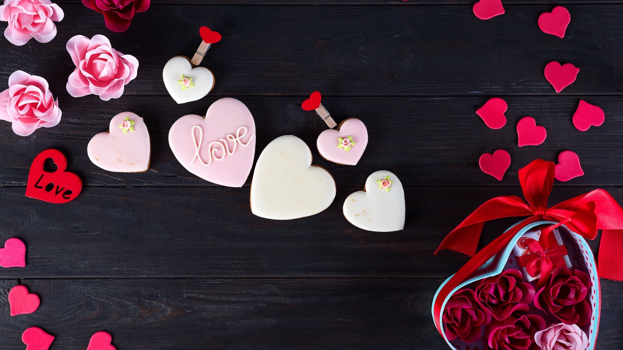 Печенье с глазурью на черной поверхности с сердечками и подарком