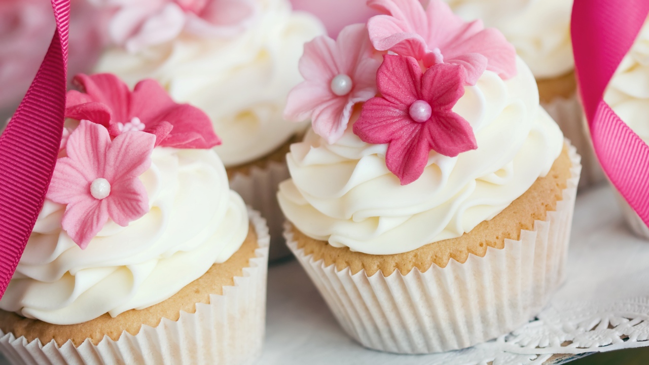 Cupcakes with cream and pink flowers close up