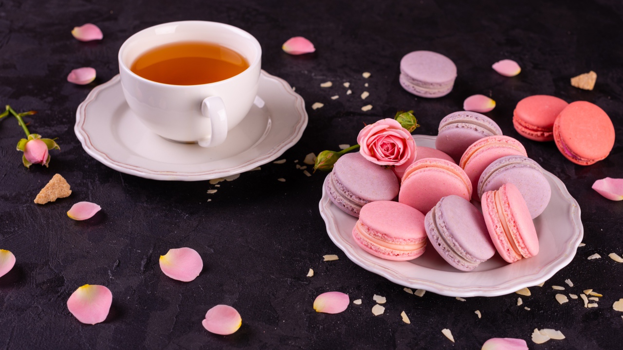 Нежный десерт макарон на столе с чашкой чая и розой