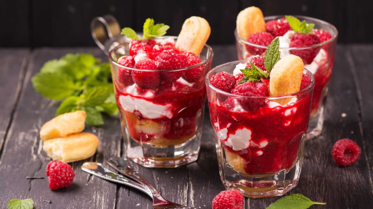 Десерт с печеньем и малиной на столе с вилками