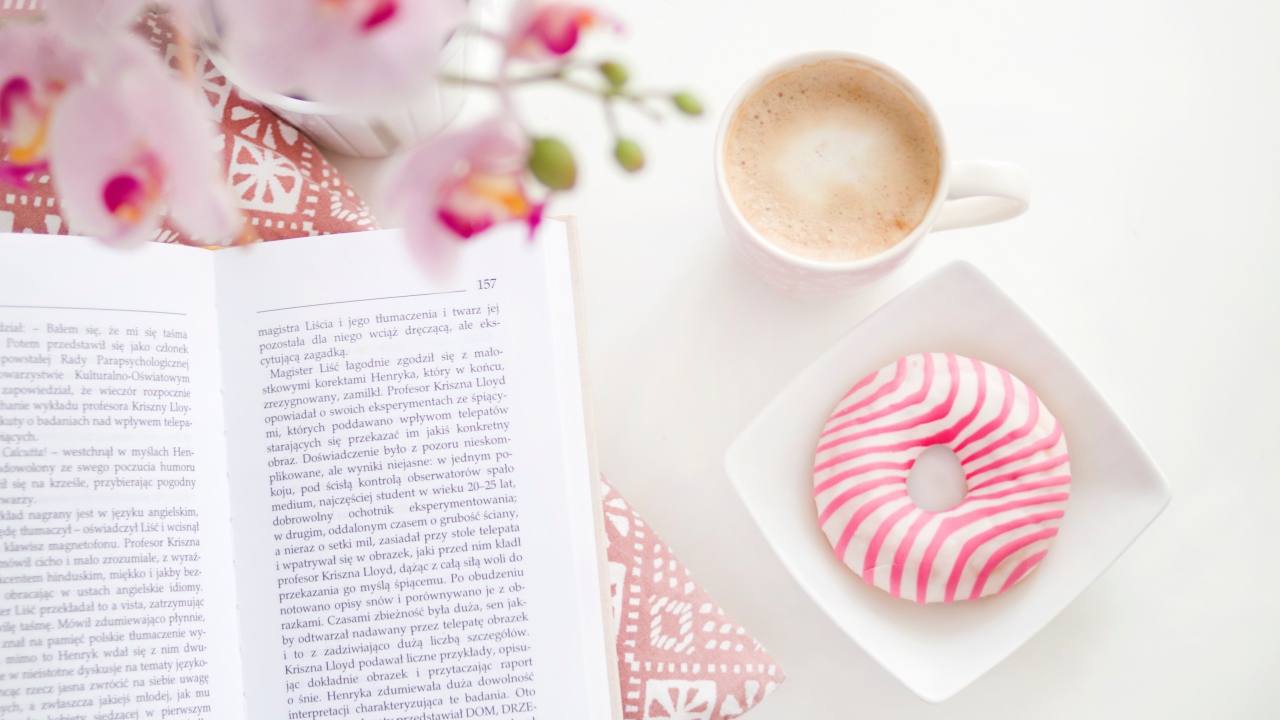 Donut with a cup of coffee on the table with a book