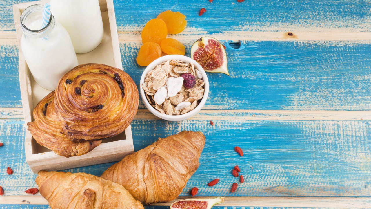 Свежая выпечка, молоко и мюсли на завтрак на столе