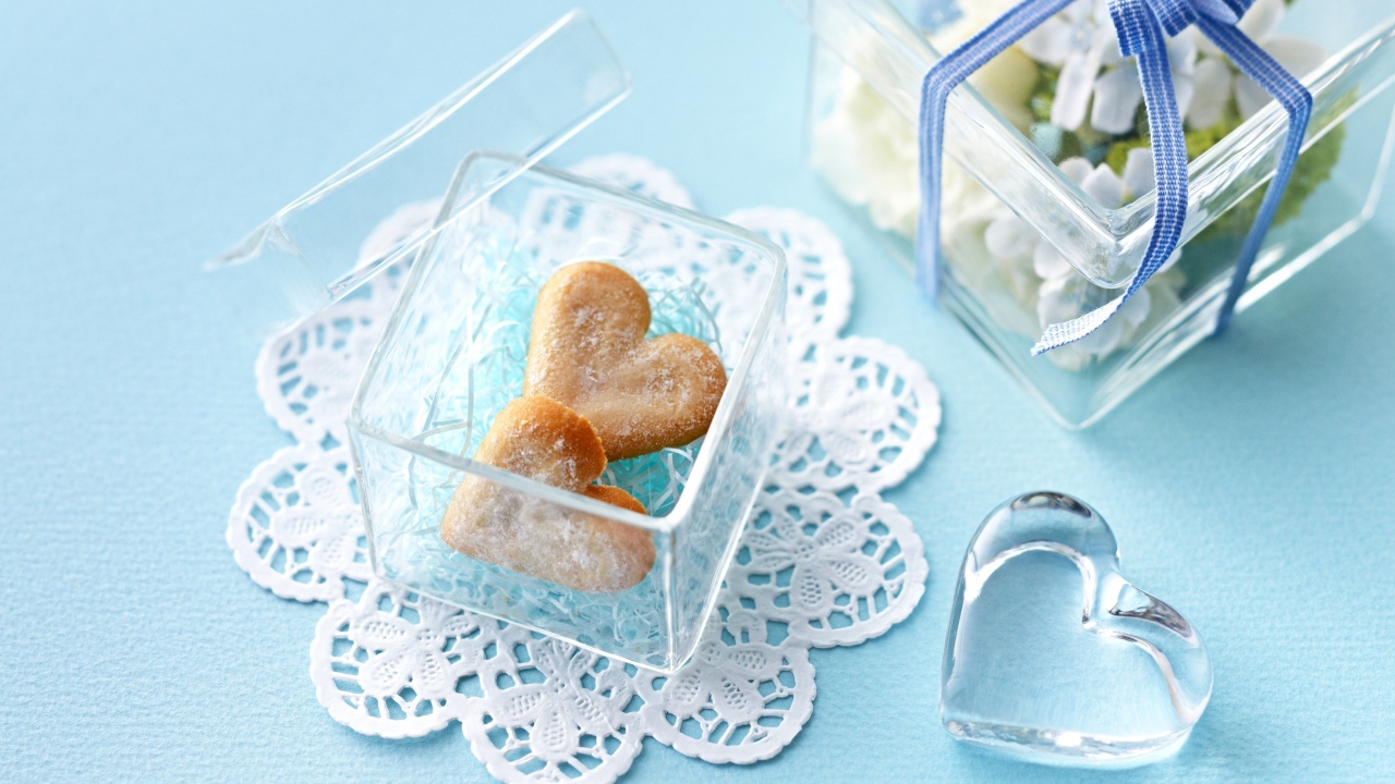 Песочное печенье в форме сердца в стеклянной шкатулке на голубом столе 