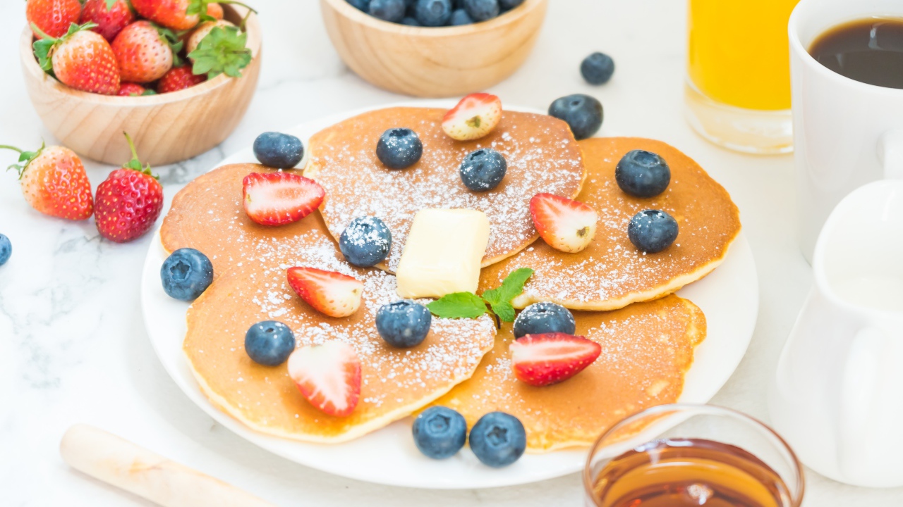 Оладьи с сахарной пудрой, клубникой и черникой на столе