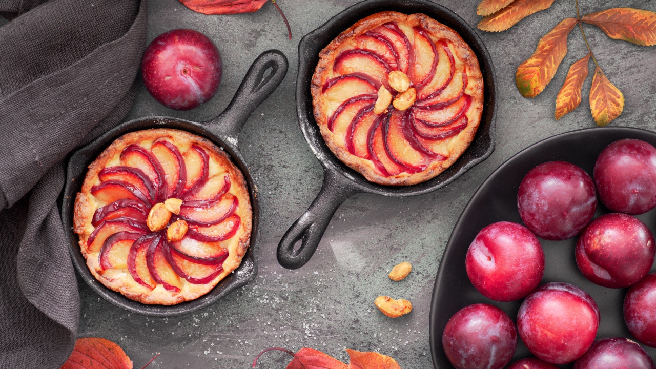 Пирог на столе с розовыми крупными сливами