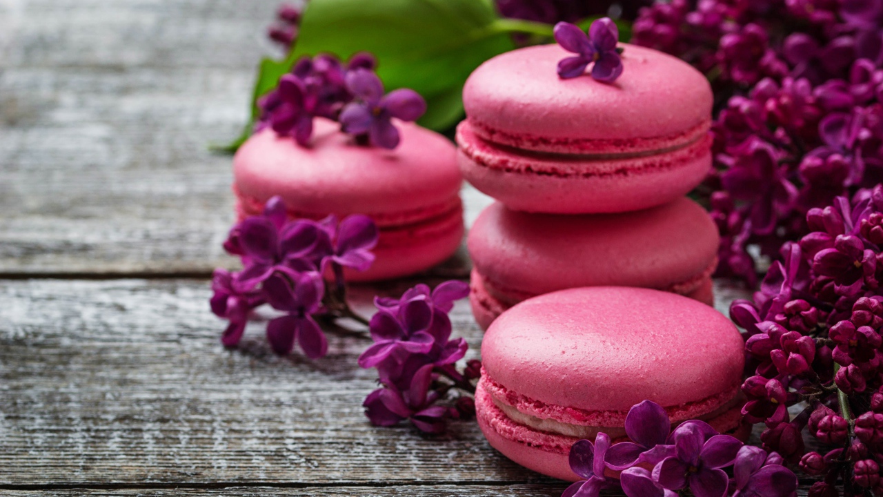 Розовый десерт макарон на столе с сиренью