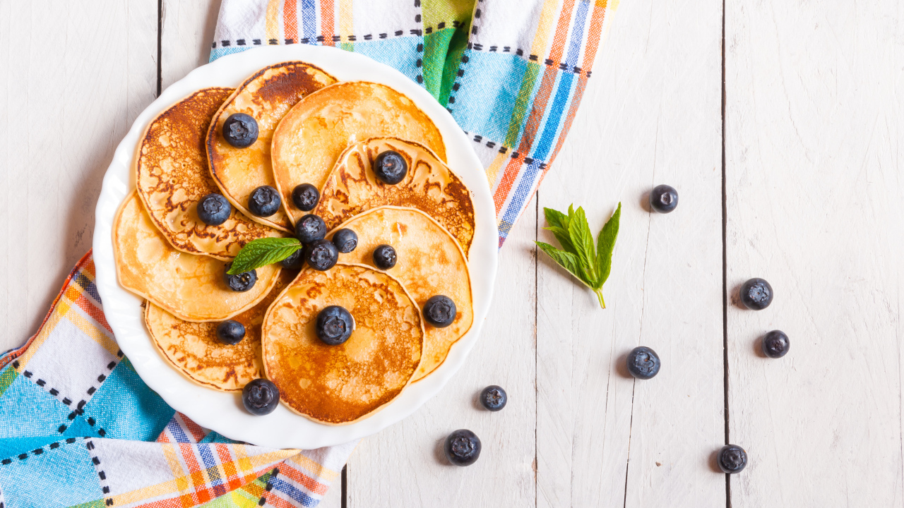 Румяные оладьи на тарелке с ягодами черники