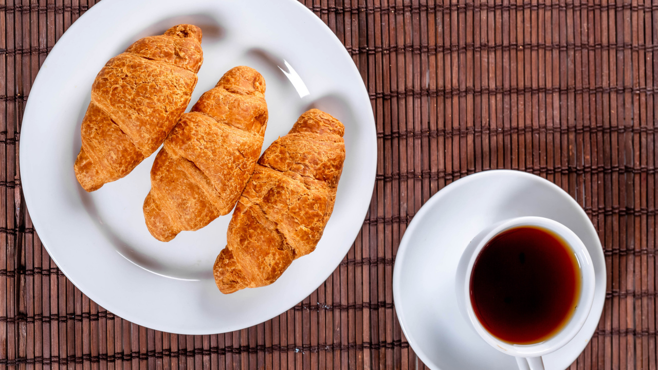 Три круассана на белой тарелке на столе с чаем