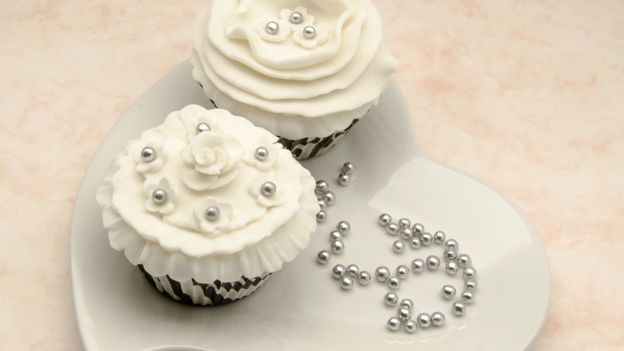 Два кекса к белым кремом на тарелке в форме сердца