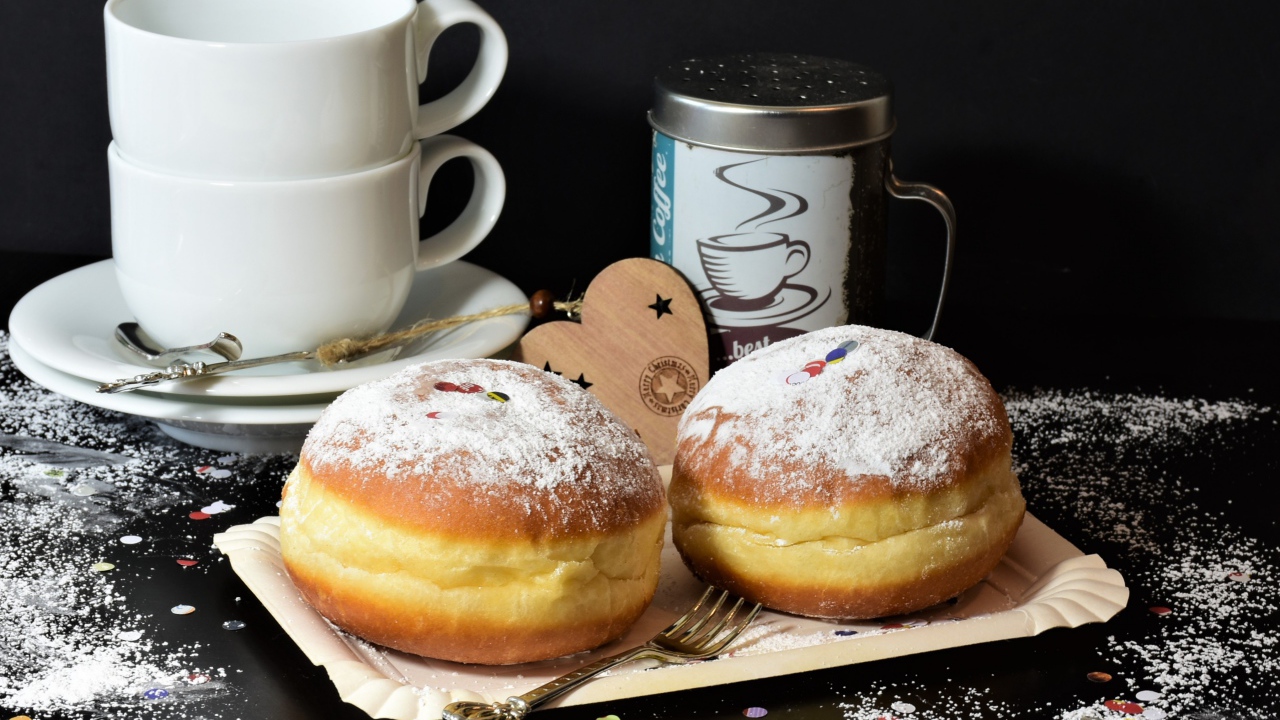Два пончика с сахарной пудрой на черном фоне с белыми чашками