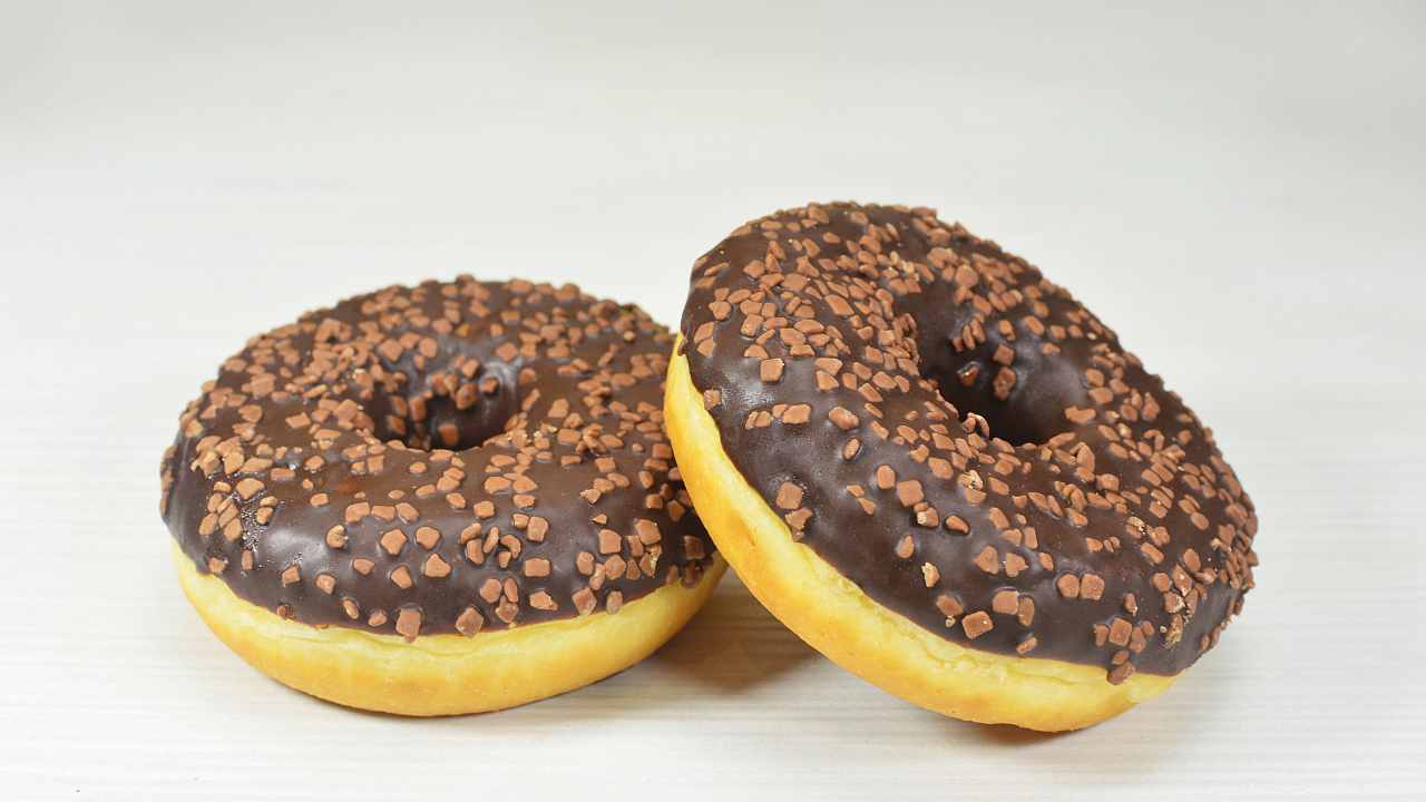 Два сладких пончика с шоколадом на сером фоне
