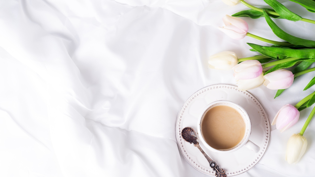 Чашка кофе на белом покрывале с тюльпанами