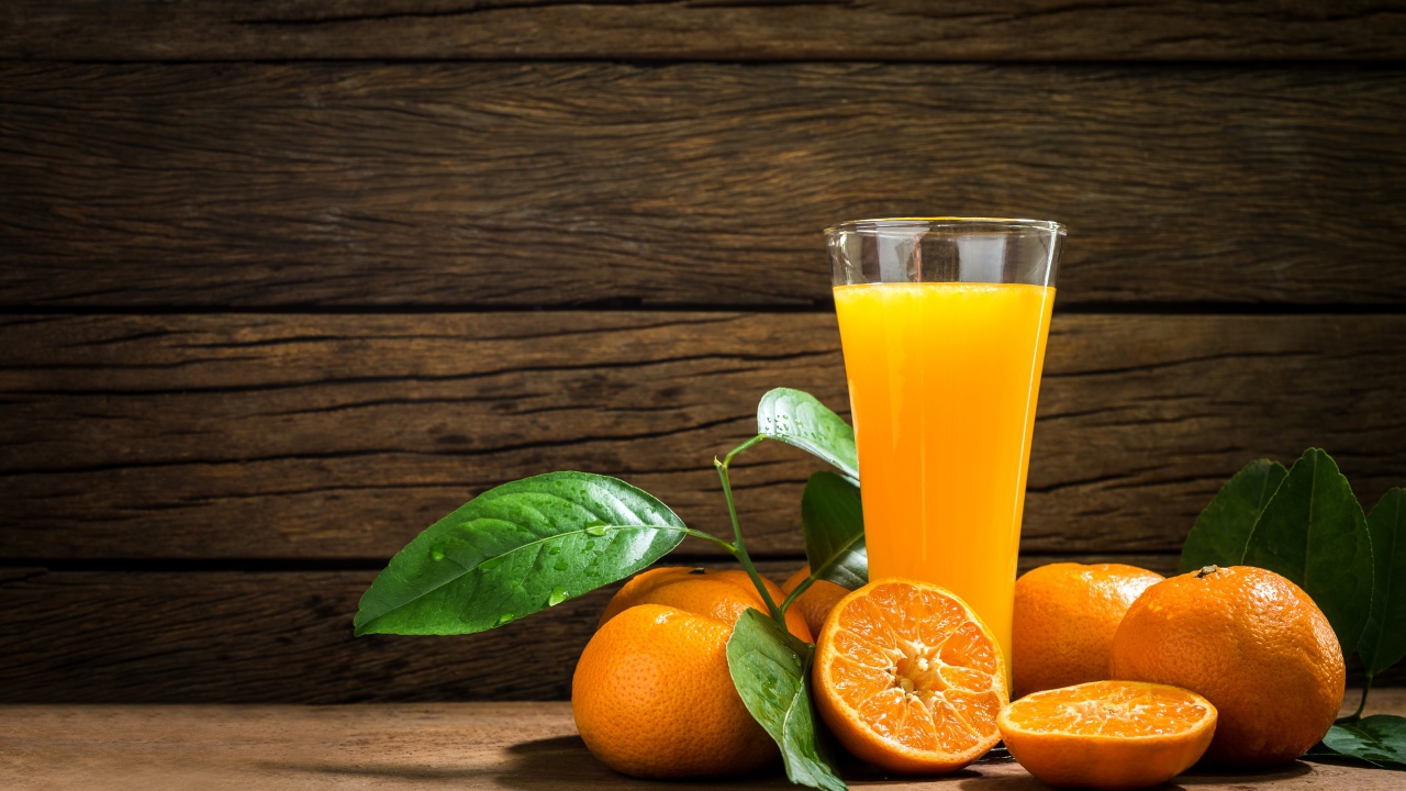 Стакан апельсинового сока на столе с мандаринами