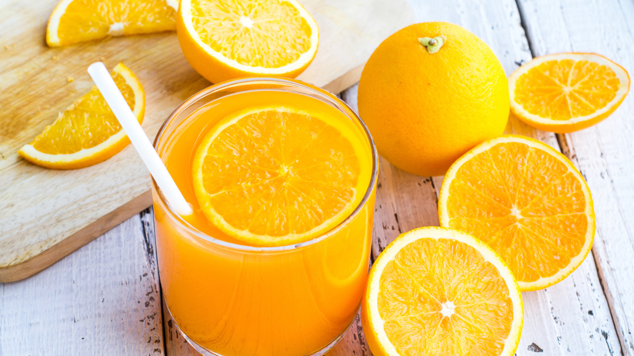 Стакан апельсинового сока на столе со свежими апельсинами на столе